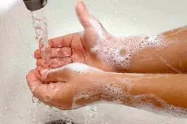 A child's hands washing under running water in a sink